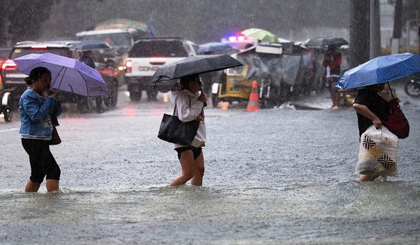 Orang ramai mengharungi jalan yang dinaiki air di Manila, selepas hujan lebat menyebabkan banjir ditambah dengan angin monsun/ AFP