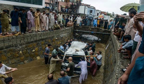 Orang ramai mengeluarkan van dari longkang selepas hujan monsun lebat di Islamabad/ AFP