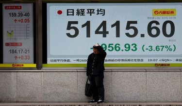 Seorang lelaki berdiri di hadapan papan paparan harga saham yang menunjukkan kadar pertukaran dolar Amerika Syarikat berbanding yen Jepun serta purata indeks Nikkei di luar sebuah firma broker di Tokyo, Jepun/ REUTERS