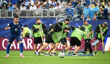 France's forward #10 Kylian Mbappe warms up next to staff workers draining the water from the field as the 2026 World Cup Group I football match between France and Iraq is suspended due to adverse weather at the Philadelphia Stadium in Philadelphia on June 22, 2026.  (Photo by Jewel SAMAD / AFP)