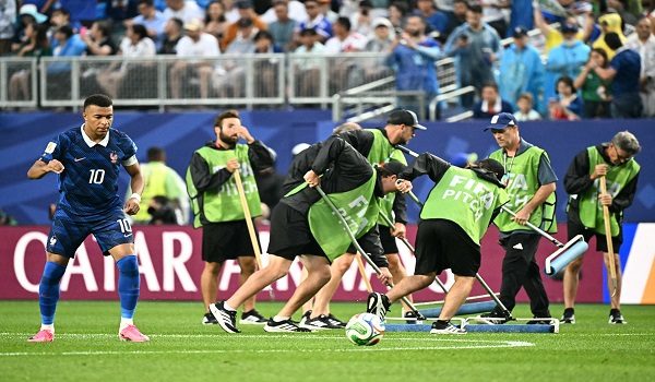 France's forward #10 Kylian Mbappe warms up next to staff workers draining the water from the field as the 2026 World Cup Group I football match between France and Iraq is suspended due to adverse weather at the Philadelphia Stadium in Philadelphia on June 22, 2026.  (Photo by Jewel SAMAD / AFP)