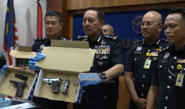 Datuk Muhamad Zaki Harun (dua dari kiri) memegang dua pucuk pistol yang dirampas