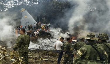 This screen grab shows soldiers and rescuers near an Air Force Hercules emitting thick smoke after the aircraft crashed during takeoff in Puerto Leguizamo, Colombia, near the southern border with Ecuador, on March 23, 2026. Colombia's military said on March 23 that about 80 troops were believed to be dead after a transport plane crash in the south of the country. (Photo by daniel ortiz / AFP)