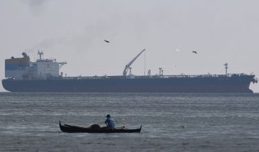 Seorang nelayan mengayuh perahu berhampiran kapal Sara Sky yang berlabuh di pelabuhan Limay, wilayah Bataan, membawa minyak mentah dari Rusia /Foto AFP