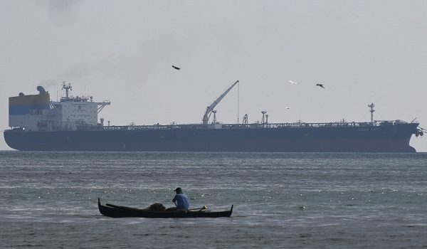 Seorang nelayan mengayuh perahu berhampiran kapal Sara Sky yang berlabuh di pelabuhan Limay, wilayah Bataan, membawa minyak mentah dari Rusia /Foto AFP