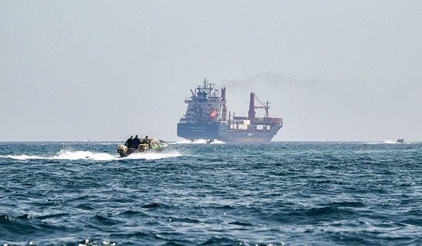 (FILES) A boat approaches the St Kitt's and Nevis-flagged container ship Marsa Victory while crusing in the waters of the Strait of Hormuz off the coast of Khasab in Omans northern Musandam peninsula on June 25, 2025. The US president sent a peace plan to Iran as he voiced optimism on March 25, 2026 at ending nearly a month of warfare, with Tehran announcing that it will let "non-hostile" oil vessels go through the crucial Strait of Hormuz. Oil prices dropped sharply and stocks in Asia rose on broader de-escalation hopes following nearly four weeks of war, as the US president appeared to be ramping up efforts to bring an end to his joint military operation with Israel. (Photo by Giuseppe CACACE / AFP)