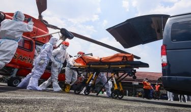 Members of a search and rescue team, wear protective suits, transfer a body bag containing a victim from the MV Virgo Transport 8, onto an ambulance from helicopter at Syamsudin Noor Air Force Base, in Banjarbaru, South Kalimantan, on September 22, 2026. The Virgo Transport 8 was carrying 213 passengers and 30 crew when it lost contact with its shipping company after departing from Indonesia's second city of Surabaya on Java island, headed for Banjarmasin on Borneo. (Photo by MUDA SAGALA / AFP)