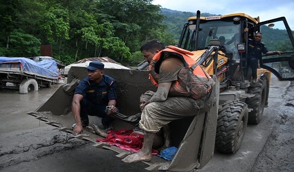 Rescue personnel use an excavator to carry a person affected by flash floods at Devghat in Nepal's Nuwakot district on August 26, 2026. Massive flooding killed eight people in Nepal on August 26, as Chinese state media reported "major casualties" from a mudslide at a Tibet trade hub on China's side of the nations' shared border. (Photo by Prakash MATHEMA / AFP)
