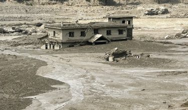 A house lies partially submerged in muddy water after flash floods at Trishuli Bazar in Nepal's Nuwakot district on August 26, 2026. A massive flood swept through Nepal's northern Rasuwa district on August 26, damaging roads and power infrastructure as authorities scrambled to assess the scale of the destruction. (Photo by Prakash MATHEMA / AFP)