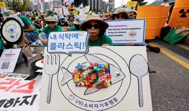 Seorang peserta perhimpunan iklim di Seoul, Korea Selatan, memegang plakad memberi amaran tentang bahaya mikroplastik dalam makanan/ Foto REUTERS