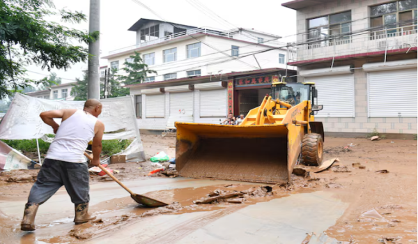 Penduduk kampung membersihkan lumpur dari jalan selepas hujan lebat menyebabkan banjir di daerah Yi, Baoding, wilayah Hebei./Foto REUTERS