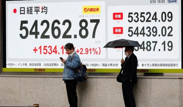 Pejalan kaki berdiri di hadapan papan paparan saham menunjukkan indeks Nikkei di luar sebuah firma broker di Tokyo, Jepun/Foto REUTERS