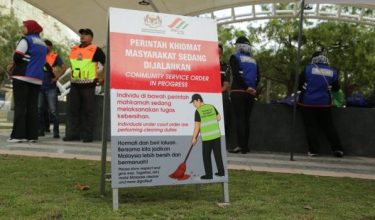 Pesalah menjalani kerja pembersihan di Putrajaya di bawah pemantauan pegawai penguat kuasa/Foto SWCorp