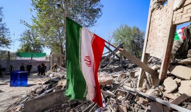 An Iranian national flag is placed by the rubble of a collapsed building following strikes at Sharif University of Technology in Tehran on April 7, 2026. Gas supply was restored on April 6 after being cut in parts of Tehran following an attack in the early hours on a gas pressure reduction station and metering facilities at Sharif University of Technology, causing a leak. (Photo by ATTA KENARE / AFP) /