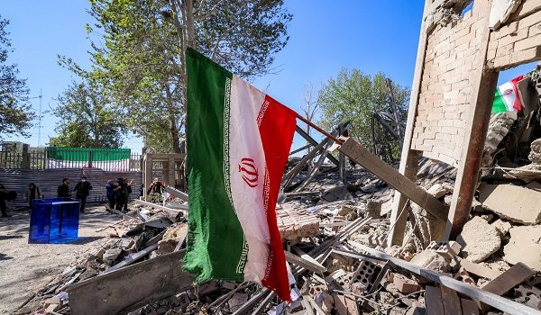 An Iranian national flag is placed by the rubble of a collapsed building following strikes at Sharif University of Technology in Tehran on April 7, 2026. Gas supply was restored on April 6 after being cut in parts of Tehran following an attack in the early hours on a gas pressure reduction station and metering facilities at Sharif University of Technology, causing a leak. (Photo by ATTA KENARE / AFP) /
