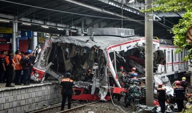 Workers clear debris at the train collision site after the locomotive of a passenger train pierced through the rear car of a commuter train at Bekasi Timur Station in Bekasi, West Java on April 28, 2026. Indonesia's president ordered an investigation on April 28 after a long-distance train smashed into a stationary commuter train overnight, killing 15 people and injuring dozens. (Photo by Rezas / AFP)